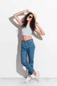 mujer-alegre-jeans-sombrero-gafas-sol-sonriendo-camara